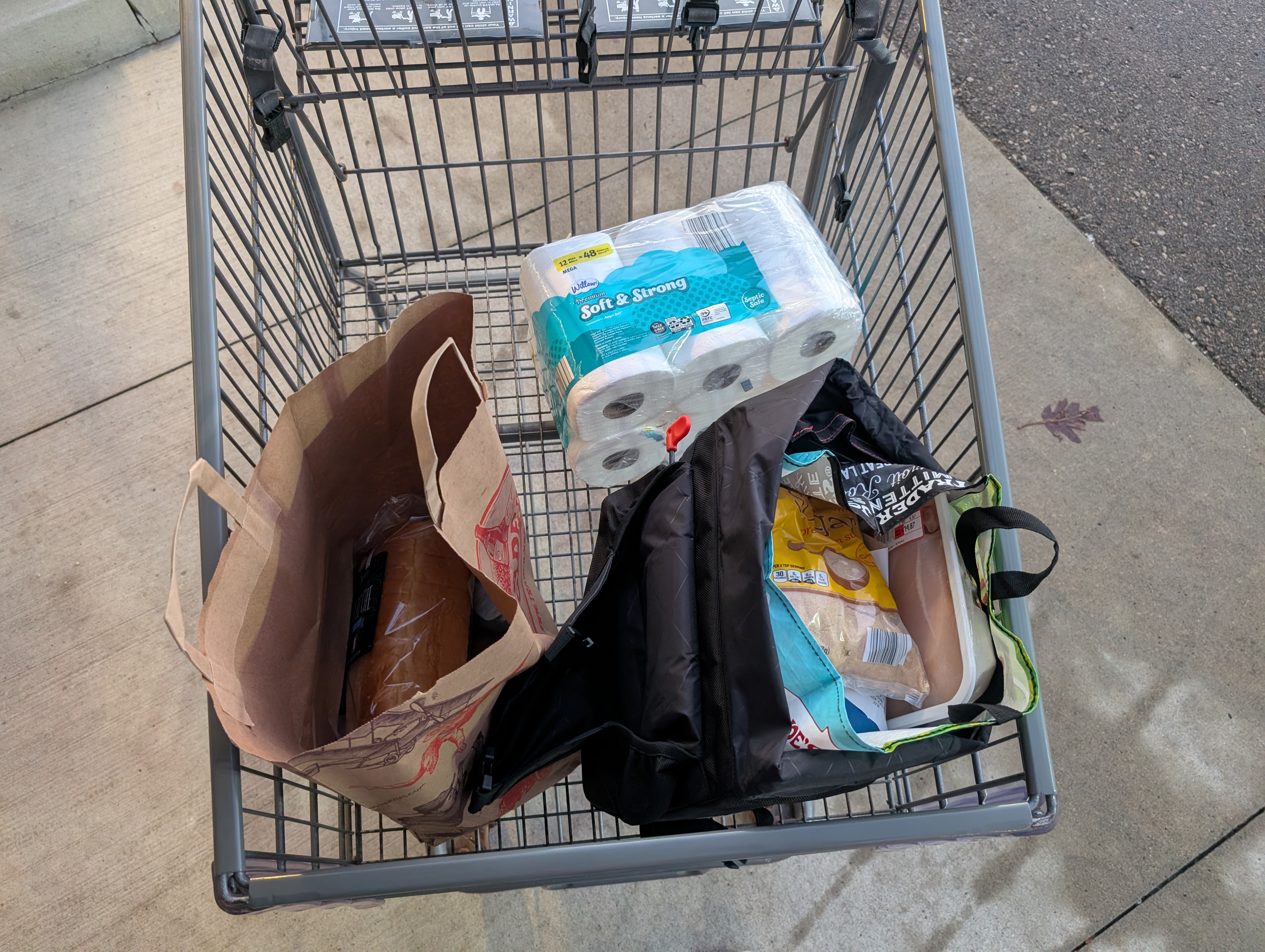 Shopping cart with two bags filled with items and twelve rolls of toilet paper