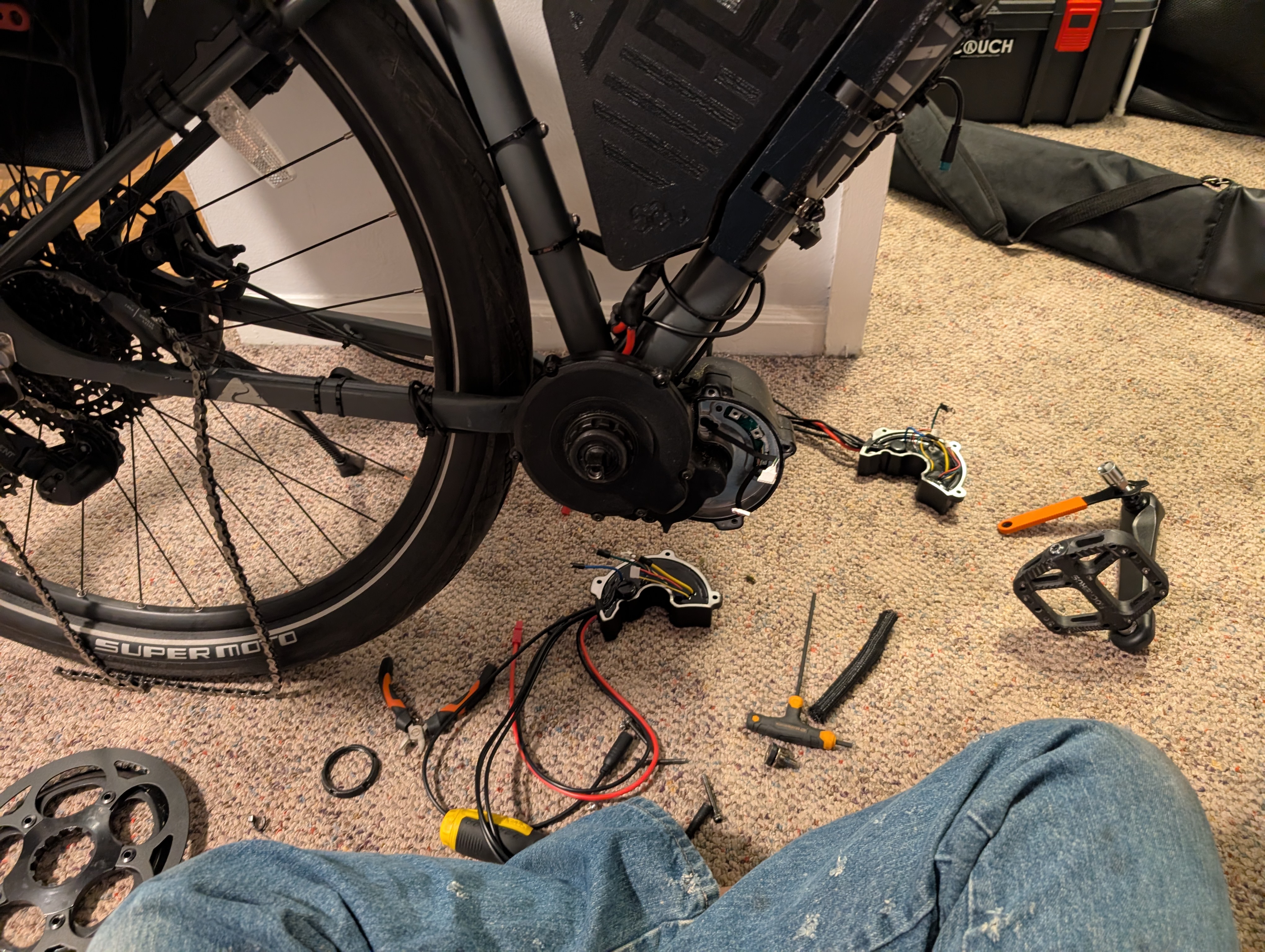 Bottom area of the bicycle with the controller missing, the old and new controller are on the floor